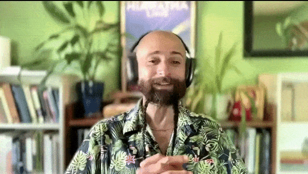 Gif of a bald man with a brown beard in two braids, wearing an Aloha shirt and headphones, talking animatedly