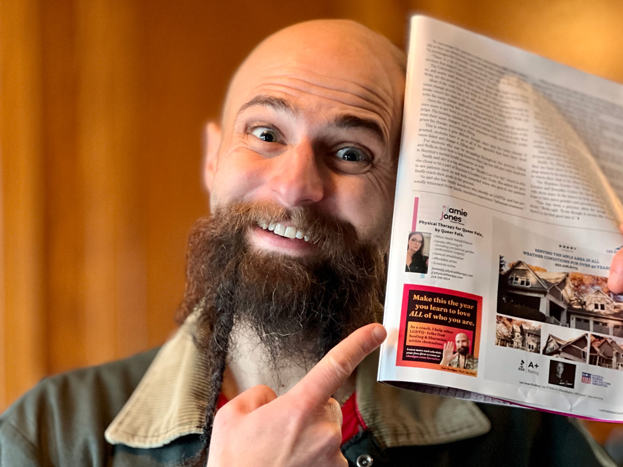 A photo of a bald white man with a beard holding up a copy of Lavender magazine.