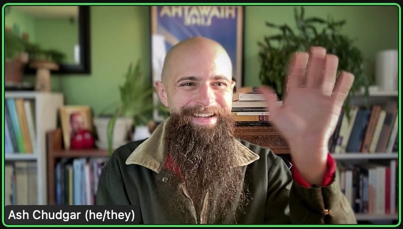 A bald man with a long brown beard in a Zoom window waves at the camera and smiles.